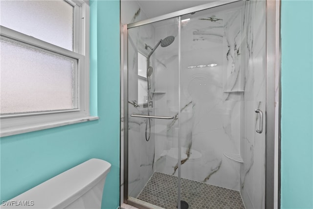 bathroom featuring a shower with door and toilet