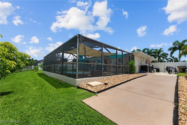 rear view of property featuring a patio, a yard, and glass enclosure