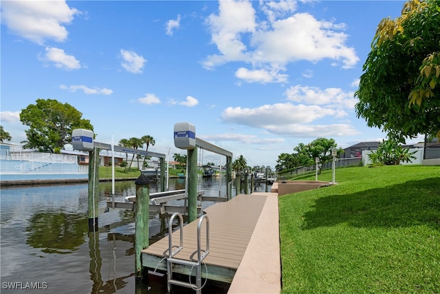 view of dock with a lawn and a water view