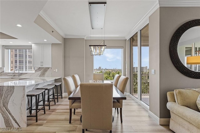 dining room with crown molding, sink, light wood-type flooring, and a notable chandelier