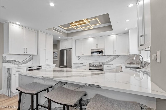 kitchen featuring light stone counters, sink, white cabinets, and stainless steel appliances