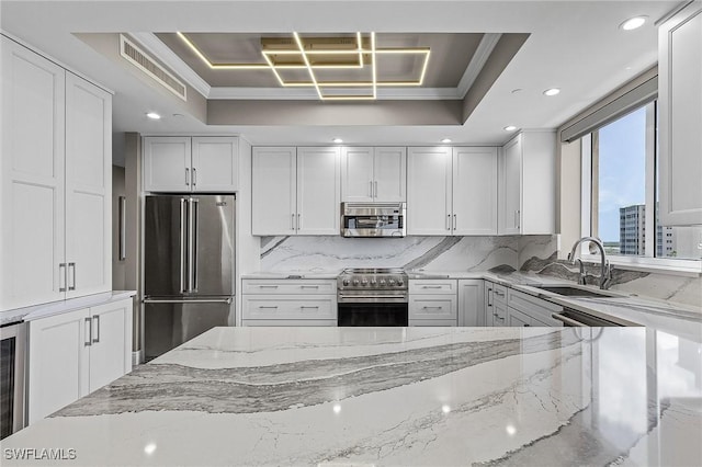 kitchen featuring stainless steel appliances, crown molding, a tray ceiling, and sink