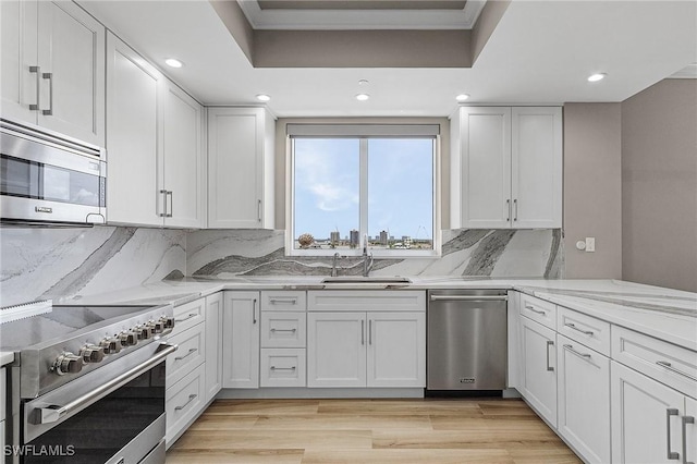 kitchen with white cabinetry, sink, light stone counters, and appliances with stainless steel finishes