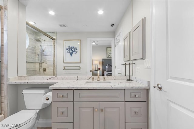 bathroom featuring a shower with door, vanity, and toilet