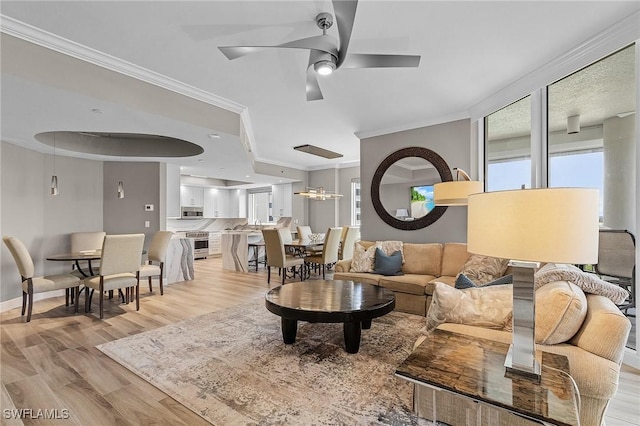 living room featuring light hardwood / wood-style floors, ceiling fan, and crown molding