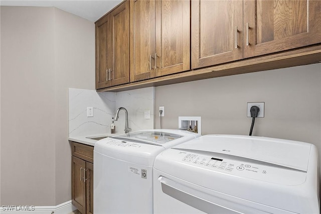 clothes washing area featuring cabinets, sink, and washing machine and clothes dryer