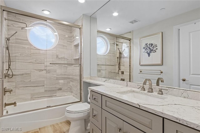 full bathroom with combined bath / shower with glass door, toilet, wood-type flooring, and vanity