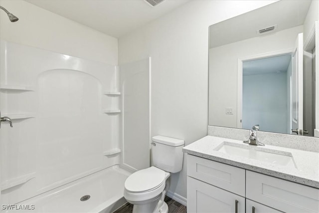 bathroom featuring vanity, wood-type flooring, toilet, and a shower