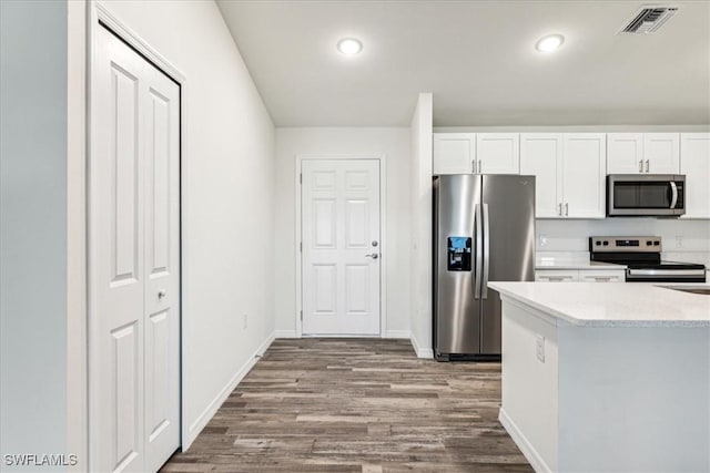 kitchen with white cabinetry, appliances with stainless steel finishes, light stone counters, and hardwood / wood-style flooring