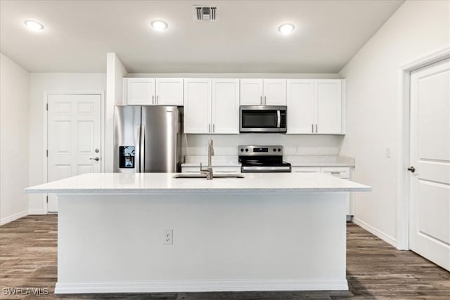 kitchen with stainless steel appliances, white cabinetry, sink, and a center island with sink