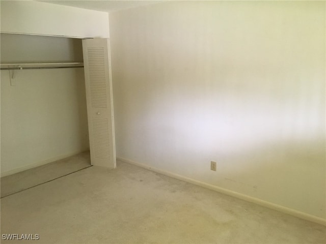 unfurnished bedroom with light carpet and a closet