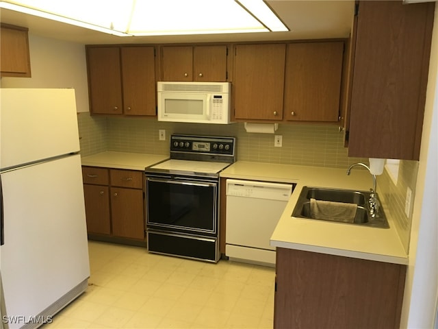 kitchen with decorative backsplash, light tile patterned floors, white appliances, and sink