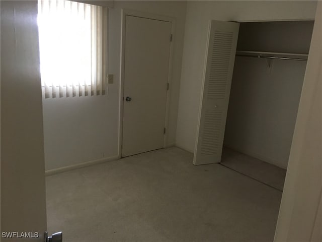 unfurnished bedroom with a closet and light colored carpet