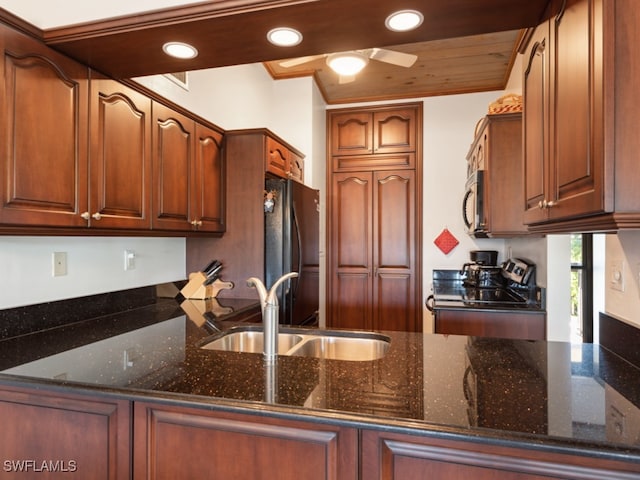 kitchen featuring stove, sink, dark stone countertops, ceiling fan, and black fridge