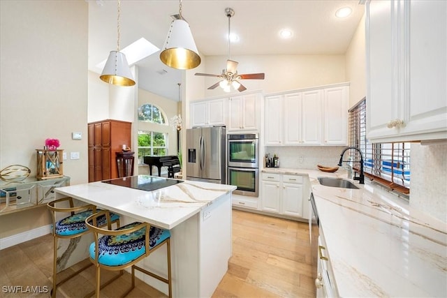 kitchen featuring white cabinets, appliances with stainless steel finishes, a center island, and sink