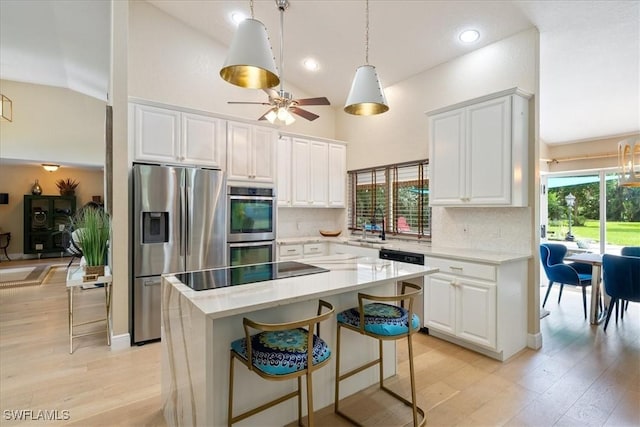 kitchen featuring white cabinets, stainless steel appliances, a kitchen island, and plenty of natural light