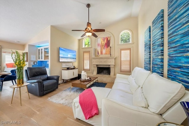 living room with a wealth of natural light, light hardwood / wood-style flooring, ceiling fan, and vaulted ceiling