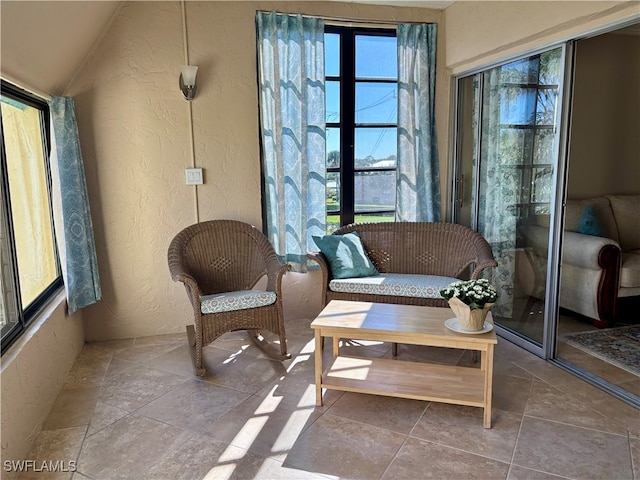 living area featuring tile patterned flooring, a wealth of natural light, and vaulted ceiling