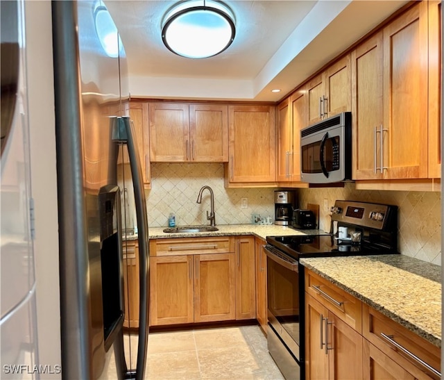 kitchen with decorative backsplash, sink, light stone countertops, and stainless steel appliances