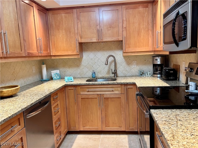 kitchen with backsplash, light stone countertops, sink, and appliances with stainless steel finishes