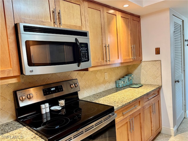 kitchen featuring decorative backsplash, light stone countertops, and appliances with stainless steel finishes