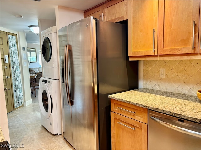 laundry room with light tile patterned floors and stacked washer and dryer