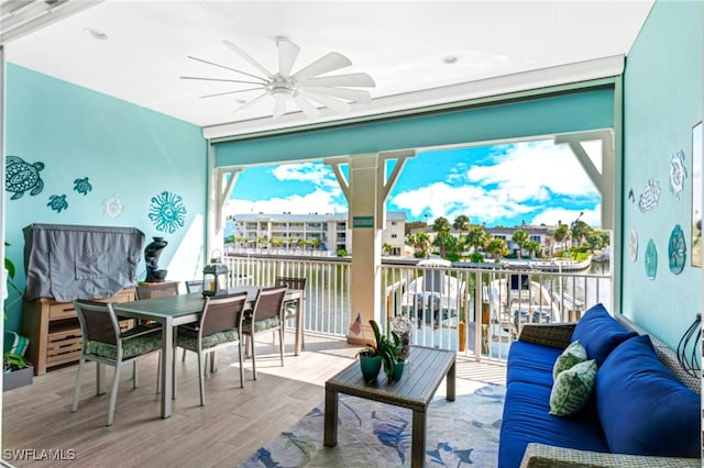 sunroom / solarium featuring ceiling fan, a water view, and a healthy amount of sunlight