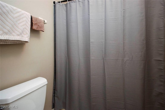 full bathroom with toilet and a shower with curtain