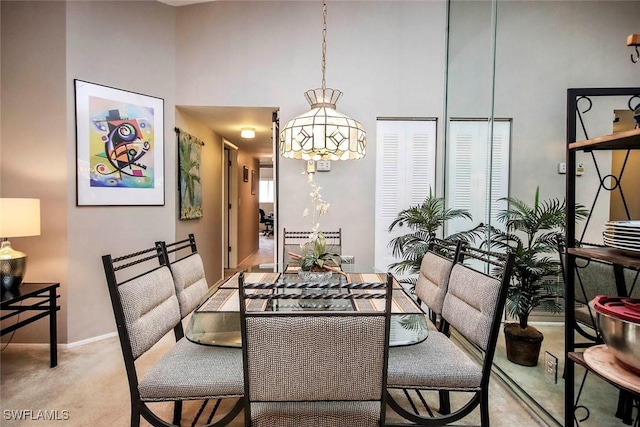 dining room with light colored carpet and a high ceiling