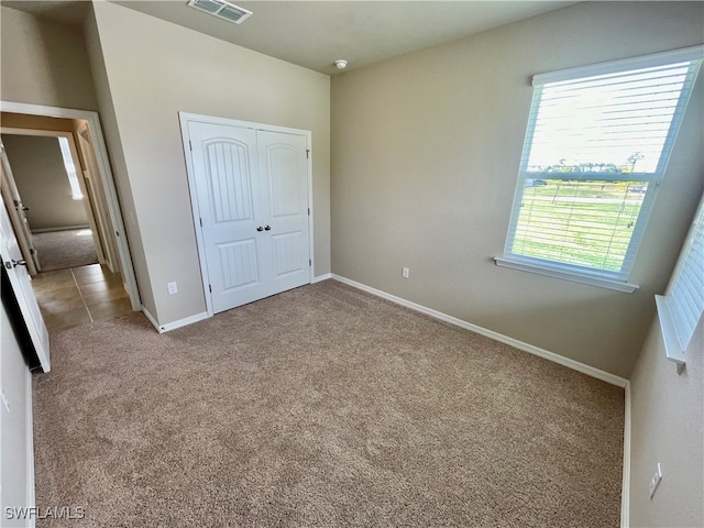 unfurnished bedroom featuring a closet and light colored carpet