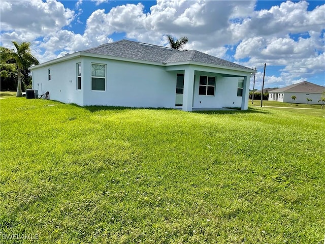 back of house with central AC unit and a lawn