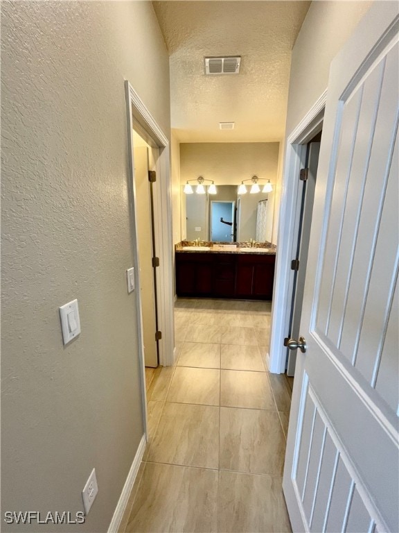 corridor with a textured ceiling and light tile patterned floors