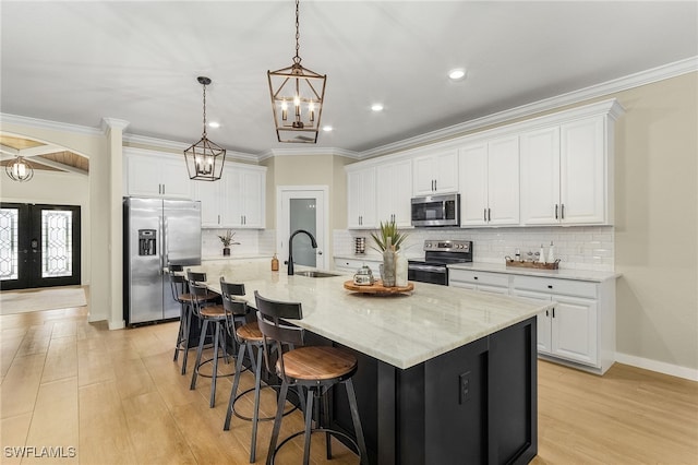 kitchen featuring sink, white cabinets, french doors, stainless steel appliances, and a center island with sink