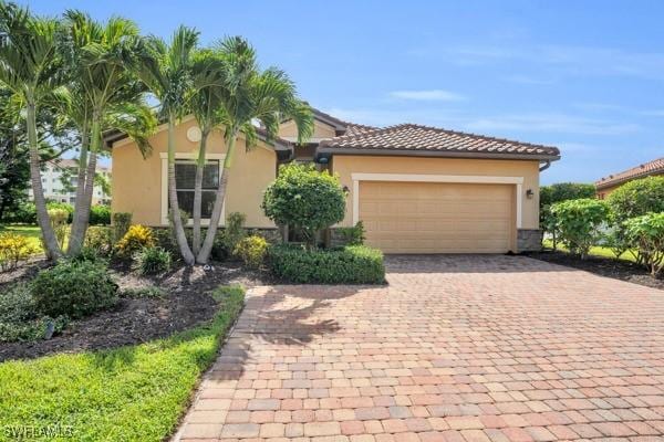 view of front of house with a garage, decorative driveway, a tile roof, and stucco siding