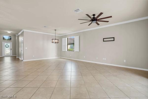 tiled empty room featuring ceiling fan with notable chandelier and ornamental molding