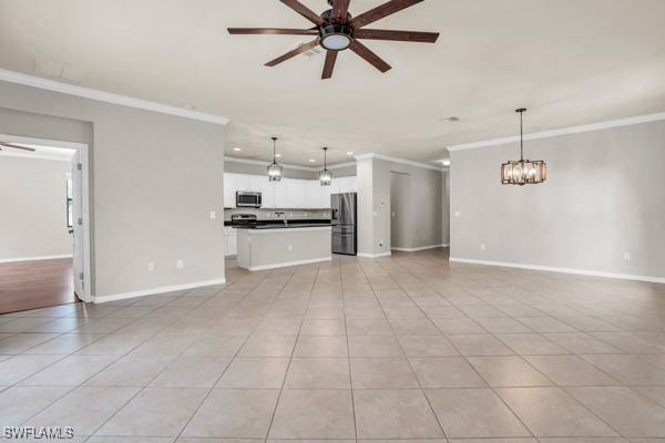 unfurnished living room featuring ceiling fan with notable chandelier, light tile patterned flooring, baseboards, and crown molding