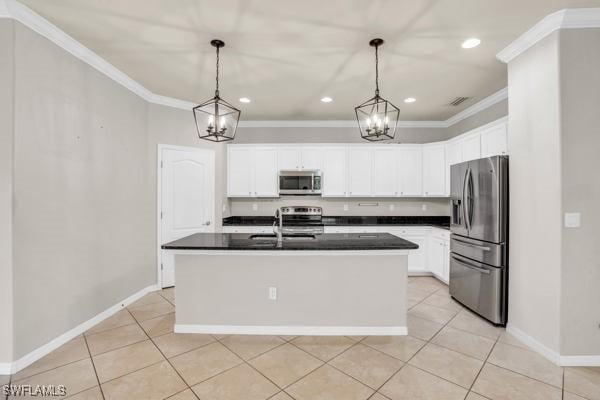 kitchen with dark countertops, stainless steel appliances, decorative light fixtures, and an island with sink