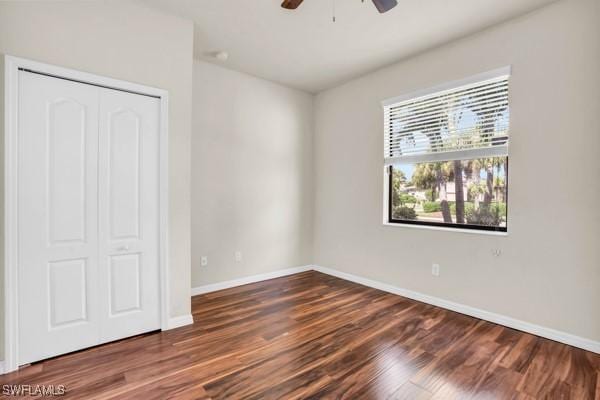 unfurnished bedroom with ceiling fan, baseboards, dark wood finished floors, and a closet