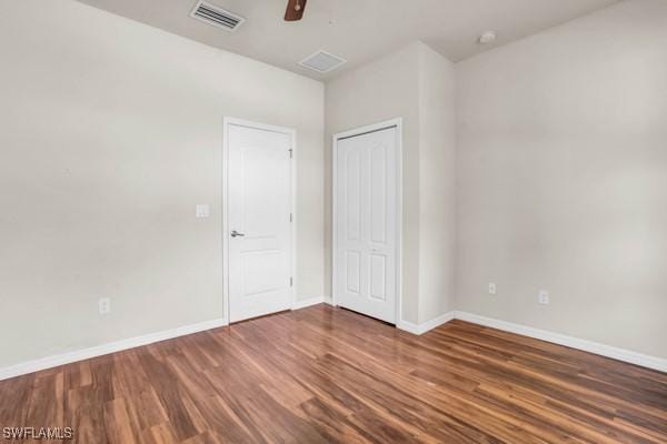 unfurnished bedroom featuring baseboards, visible vents, a ceiling fan, dark wood-style flooring, and a closet