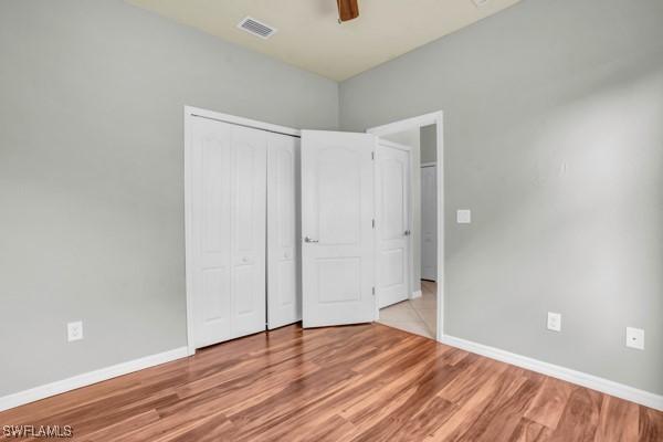 unfurnished bedroom featuring ceiling fan, light hardwood / wood-style flooring, and a closet