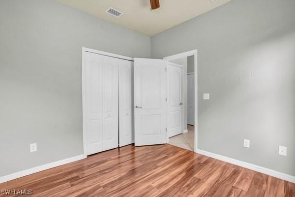 unfurnished bedroom with ceiling fan, visible vents, baseboards, light wood-style floors, and a closet