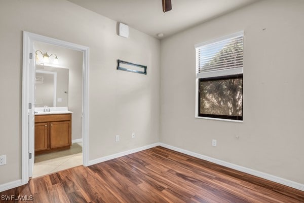 unfurnished bedroom featuring ensuite bathroom, light tile patterned floors, and ceiling fan