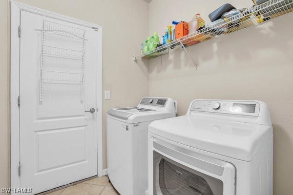 laundry area with washing machine and clothes dryer and light tile patterned floors