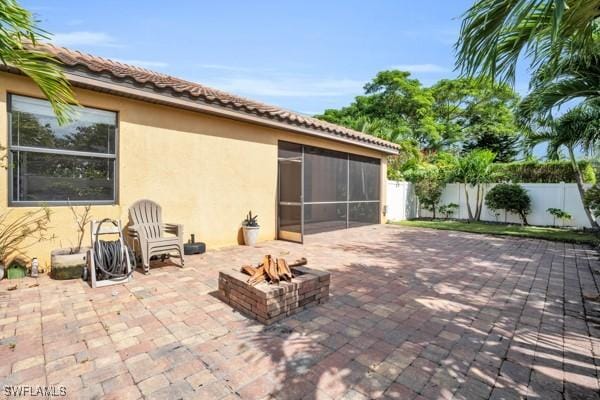 view of patio with a sunroom, a fenced backyard, and a fire pit