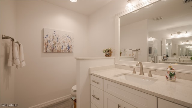 bathroom with vanity, toilet, and wood-type flooring