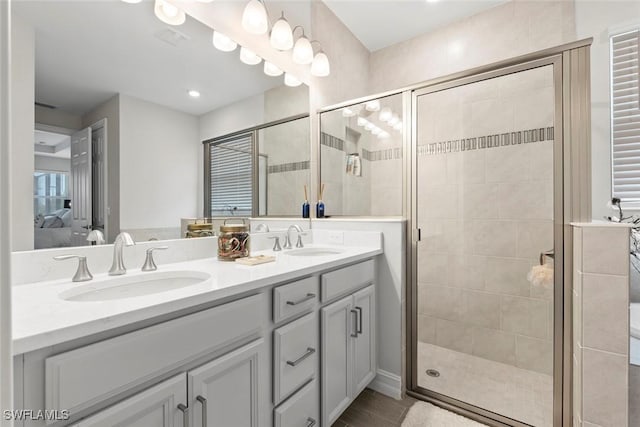 full bath featuring ensuite bathroom, double vanity, a sink, and a shower stall