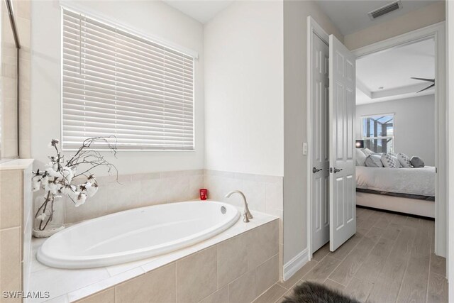 ensuite bathroom with wood finished floors, visible vents, connected bathroom, and a bath