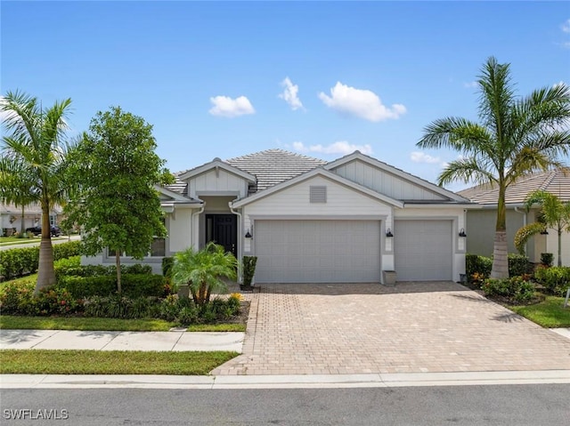 single story home featuring a garage, decorative driveway, and a tile roof