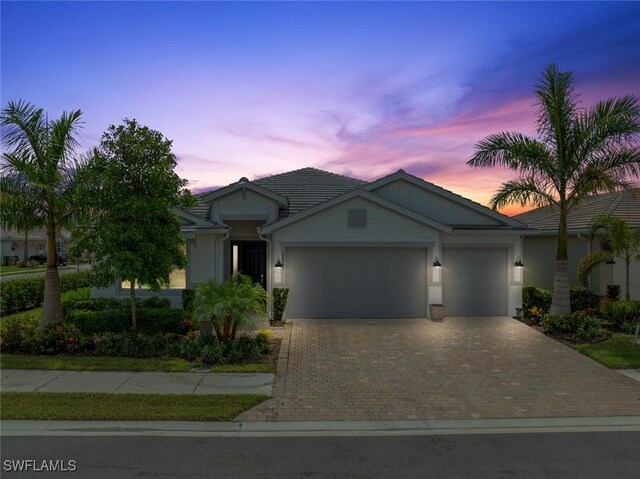 ranch-style home featuring a garage, decorative driveway, and a tile roof