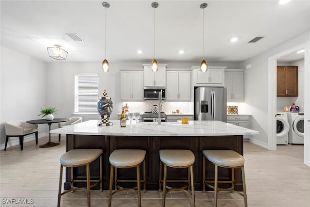 kitchen with appliances with stainless steel finishes, a spacious island, visible vents, and pendant lighting